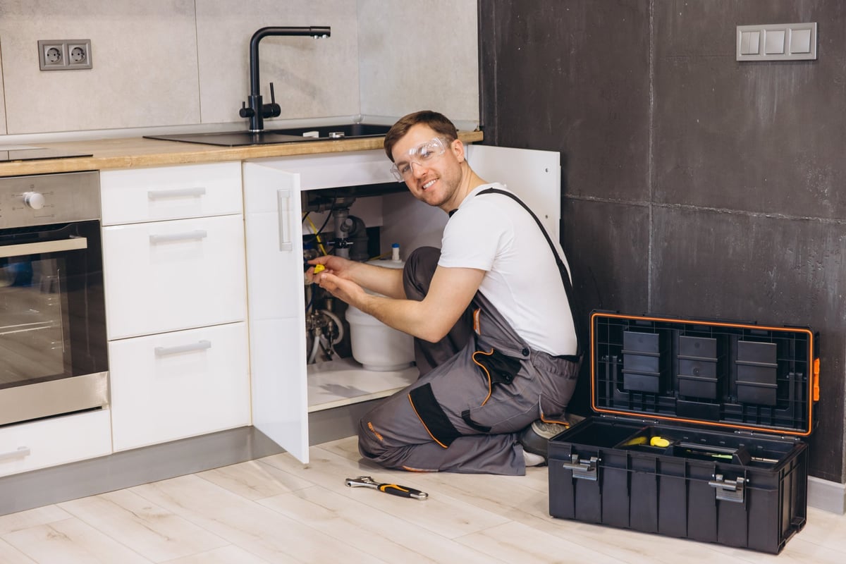 Plumber working on a fixture under a kitchen sink
