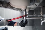 Plumber repairing water pipe under sink